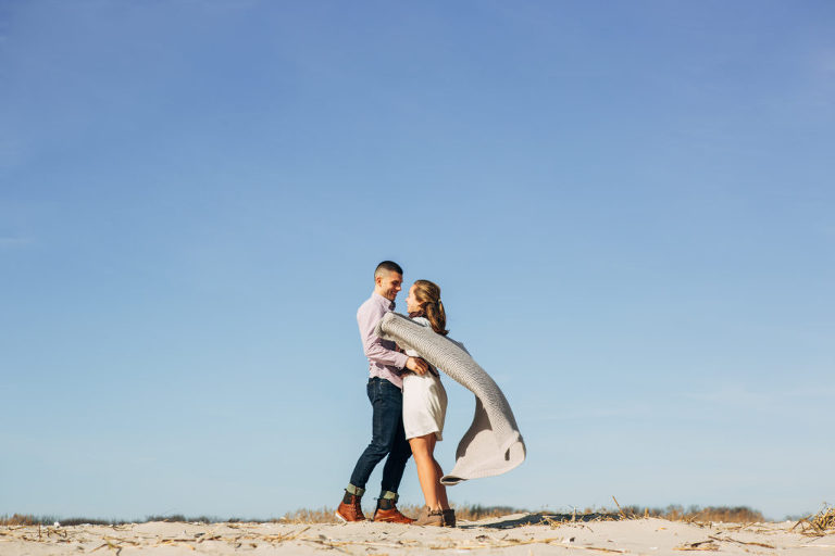 Engaged couple pose during winter beach portrait session in Ocean City, NJ