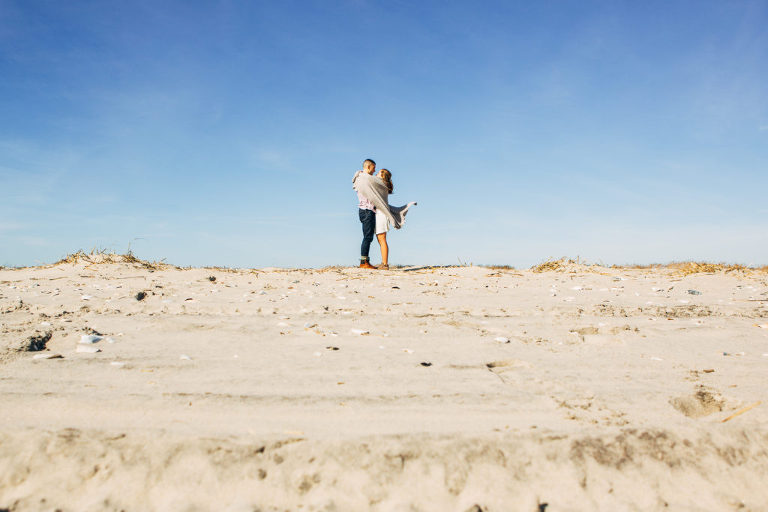 Couple poses at winter beach engagement session with Kaleidoscope Imagery