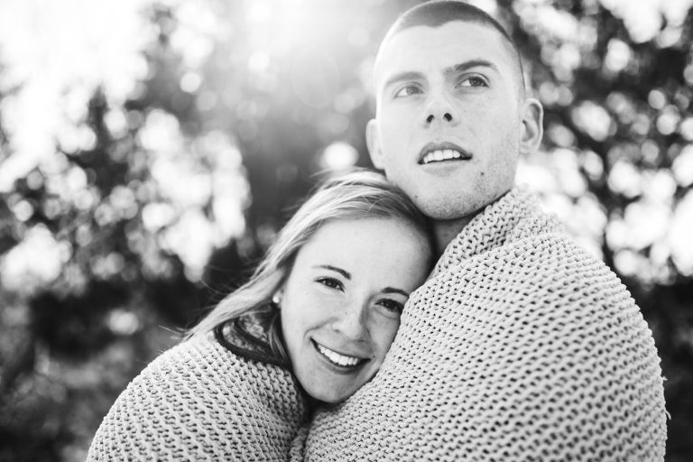 Engaged couple cuddle up at winter beach session in Corsons Inlet, NJ. 