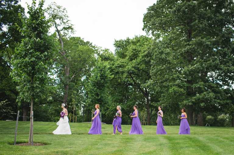 This wide angle photo shows the bride and bridesmaids walking from Cairnwood Estate to the Bryn Athyn Cathedral.