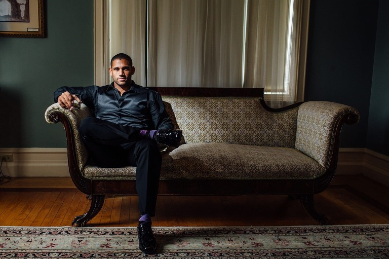 Groom poses on couch as he gets ready for his wedding at Cairnwood Estate in Bryn Athyn, PA.