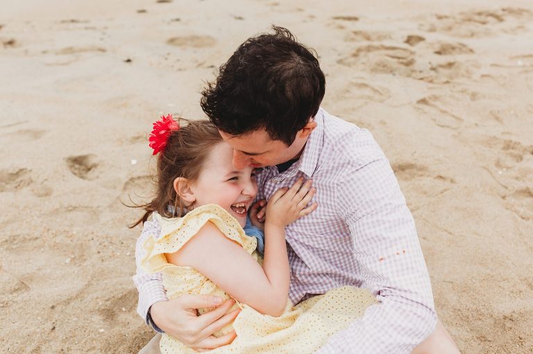 A Dad and his Daughter cuddle on beach in Belmar, NJ