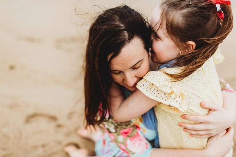 A daughter tells her mom a secret on the beach during Kaleidoscope Imagery portrait session