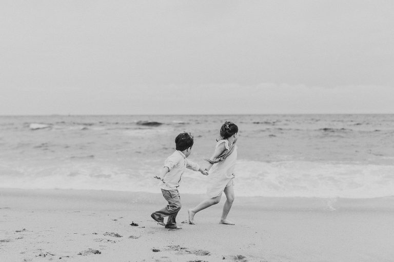 Siblings run together in the surf at Belmar, NJ