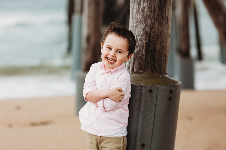 A little boy poses under the pier at Belmar Beach.